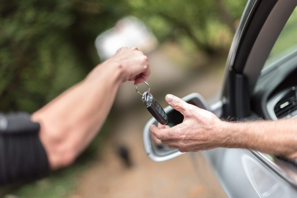 Autoschlüssel wird von einer Person übergeben.